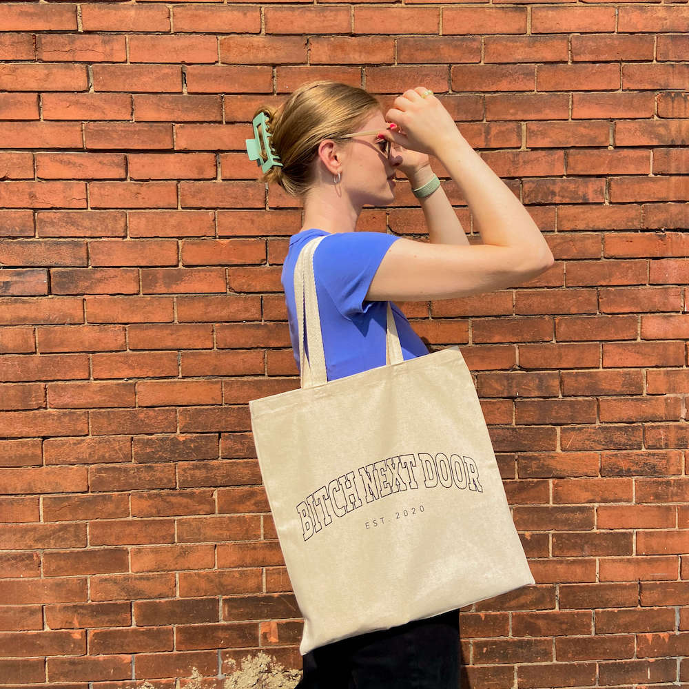 our namesake bitch next door tote bag. Nude bad and black text.