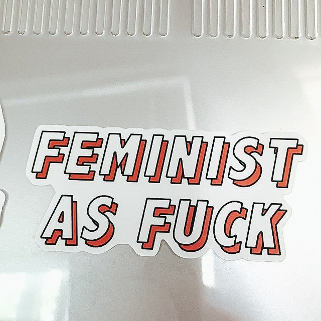 Pink and white sticker "feminist as fuck"
